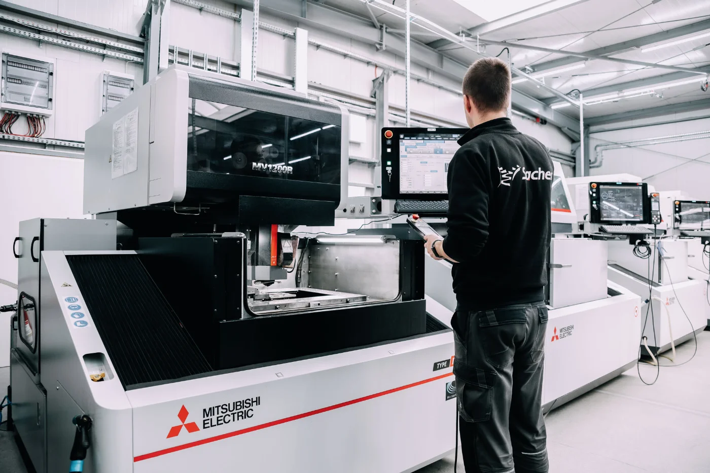 Bediener an einer Drahterodiermaschine in der Halle von Sacher CNC